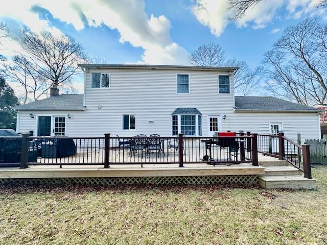 rear view of property with a wooden deck and a lawn