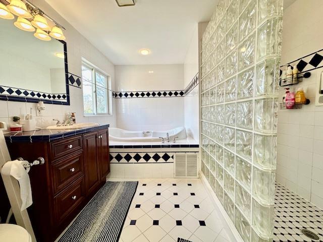 bathroom featuring vanity, independent shower and bath, tile patterned flooring, and tile walls