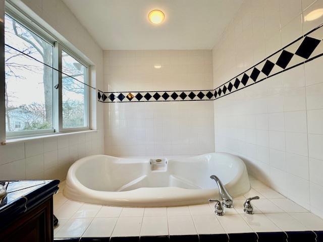 bathroom featuring vanity, tiled bath, and tile walls