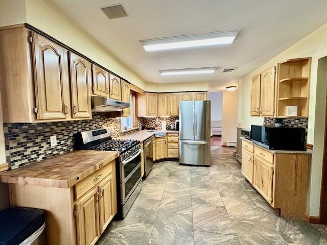 kitchen with butcher block counters, backsplash, and stainless steel appliances