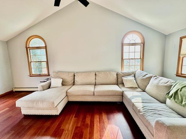 living room featuring baseboard heating, dark hardwood / wood-style flooring, and vaulted ceiling