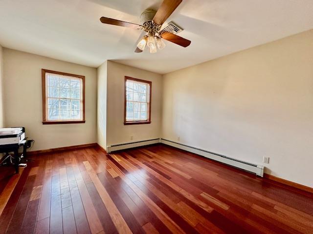 spare room with wood-type flooring, ceiling fan, and baseboard heating