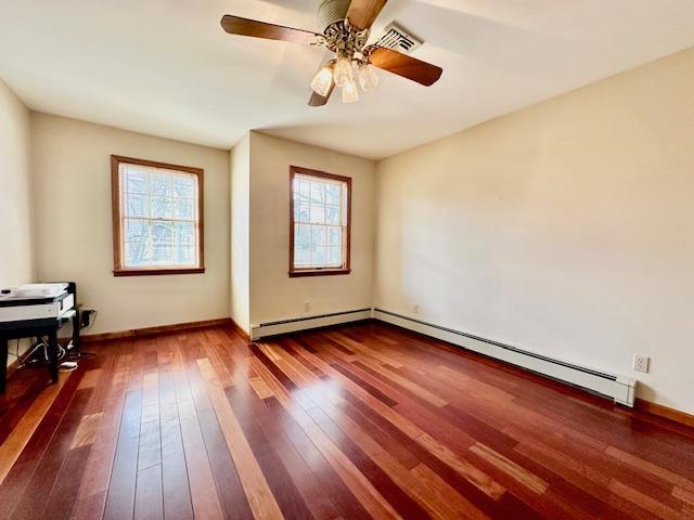 empty room featuring a baseboard heating unit, hardwood / wood-style floors, and ceiling fan