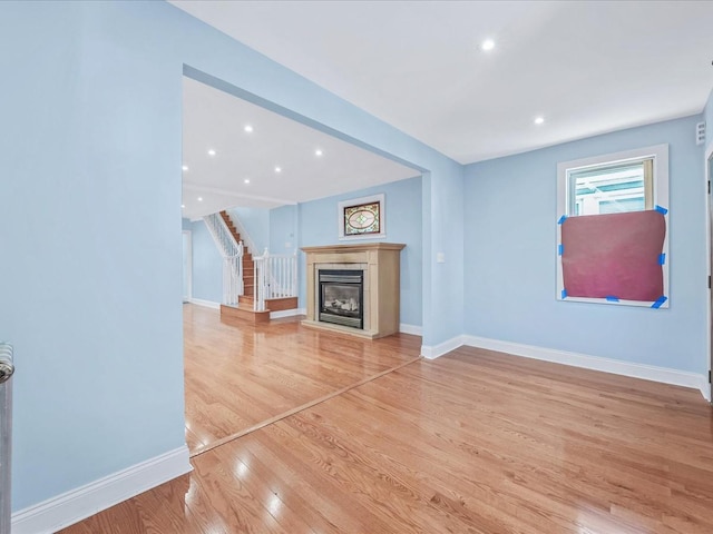 unfurnished living room featuring hardwood / wood-style flooring and a tiled fireplace