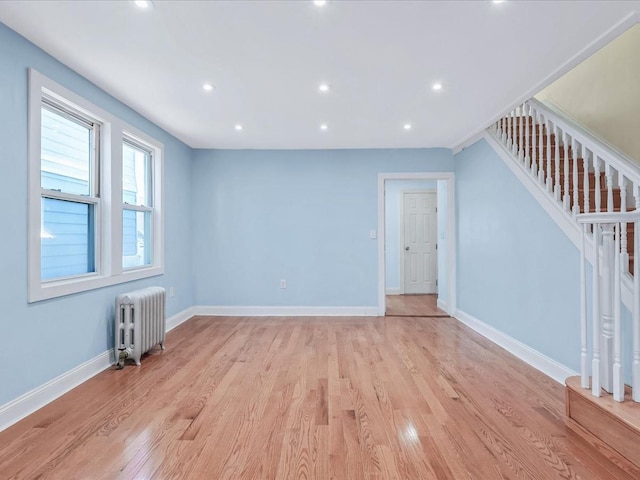 unfurnished living room featuring radiator heating unit and light hardwood / wood-style flooring