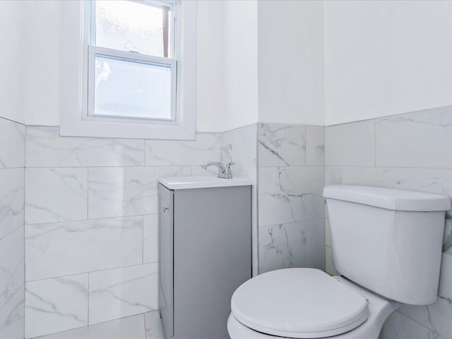 bathroom featuring vanity, tile walls, and toilet