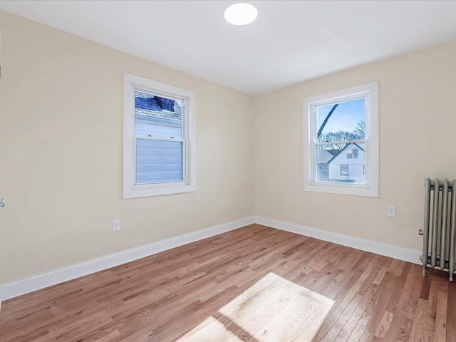 unfurnished room with radiator heating unit and light wood-type flooring