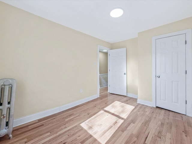 unfurnished bedroom with radiator and light hardwood / wood-style flooring