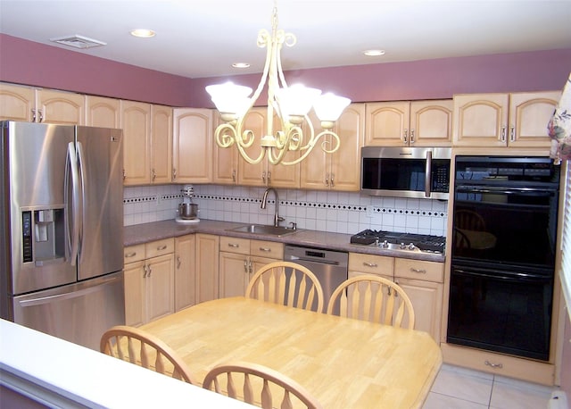 kitchen with tasteful backsplash, appliances with stainless steel finishes, sink, and hanging light fixtures