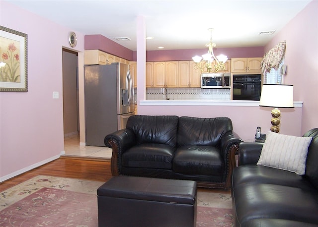 living room featuring a notable chandelier, light hardwood / wood-style flooring, and sink