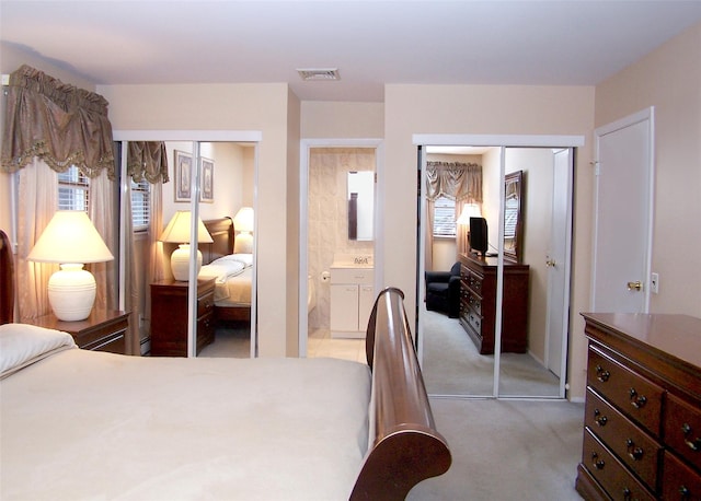 carpeted bedroom with multiple windows, a baseboard heating unit, and multiple closets