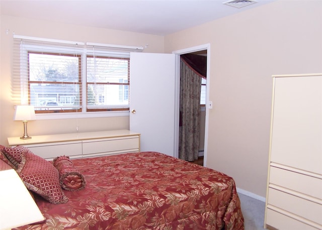 bedroom featuring multiple windows, a baseboard heating unit, and carpet floors