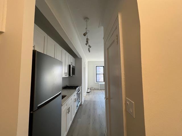 kitchen featuring white cabinetry, track lighting, appliances with stainless steel finishes, and light hardwood / wood-style floors