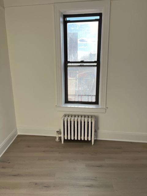 unfurnished room with radiator and hardwood / wood-style flooring