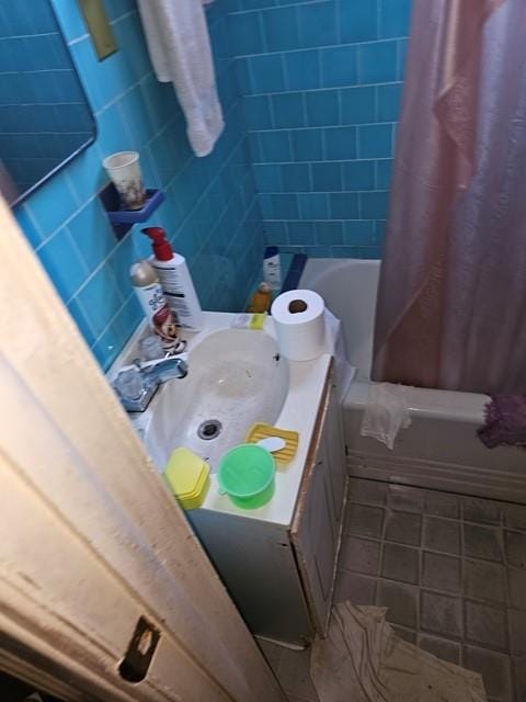 bathroom with shower / tub combo, sink, tile patterned floors, and tile walls