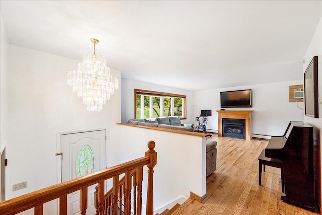 hall featuring a wall unit AC, light hardwood / wood-style floors, a chandelier, and baseboard heating