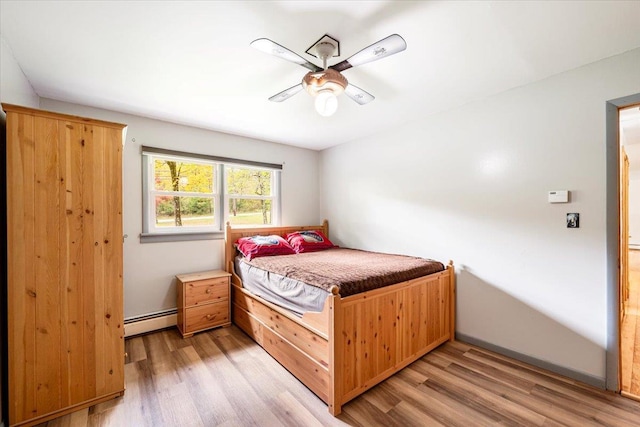 bedroom featuring ceiling fan, light hardwood / wood-style flooring, and a baseboard heating unit