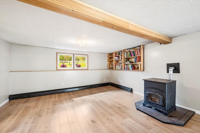 interior space with baseboard heating, wood-type flooring, a textured ceiling, and a wood stove