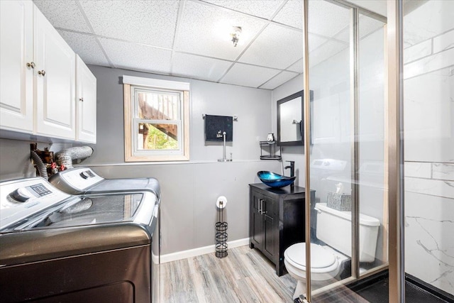 clothes washing area with washer and dryer, sink, and light wood-type flooring