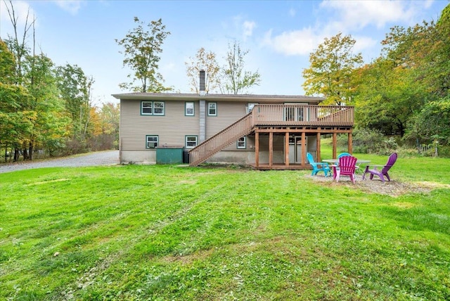 back of property with a yard, an outdoor fire pit, and a deck