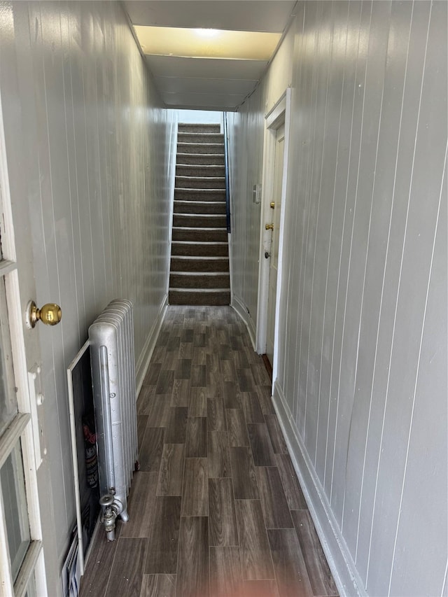 corridor with radiator heating unit, dark hardwood / wood-style floors, and wooden walls