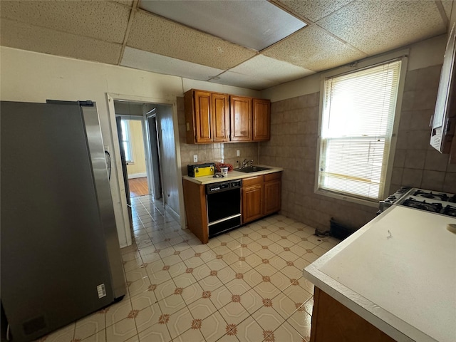 kitchen with stainless steel fridge, black dishwasher, sink, and a drop ceiling