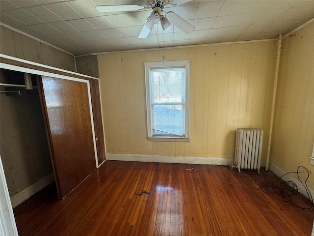 unfurnished bedroom featuring dark wood-type flooring, radiator heating unit, and crown molding