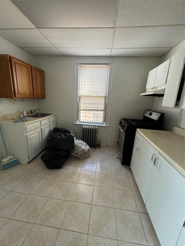 kitchen with gas range, radiator heating unit, a drop ceiling, and light tile patterned floors