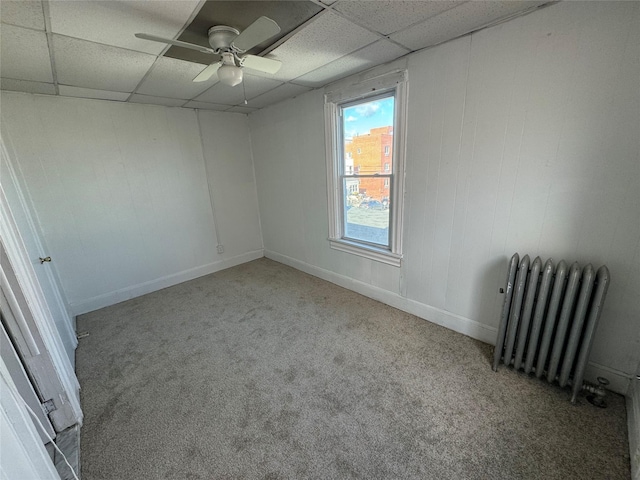 unfurnished room with light carpet, radiator heating unit, a drop ceiling, and ceiling fan