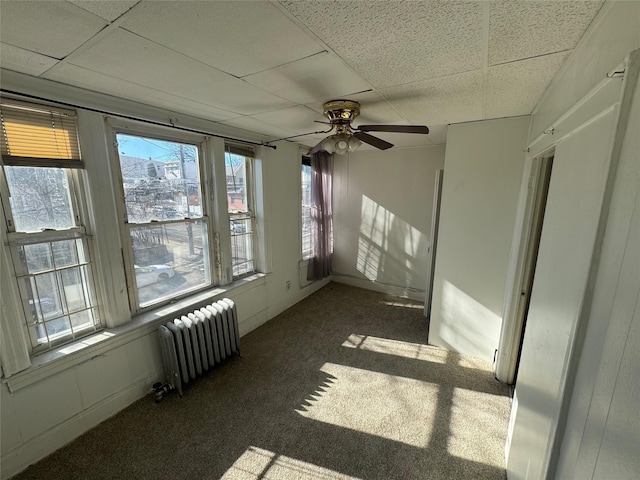 carpeted spare room featuring radiator, a paneled ceiling, and ceiling fan