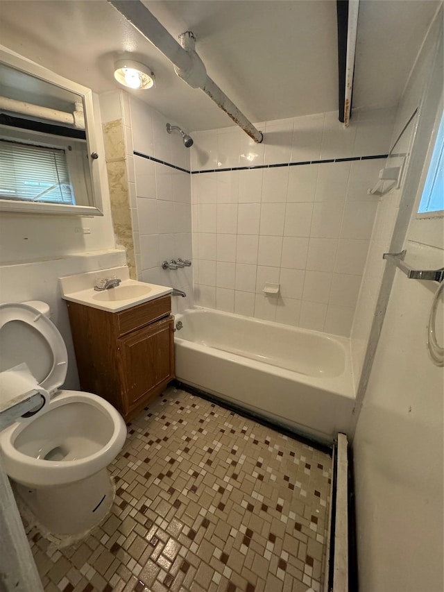 full bathroom with beamed ceiling, tiled shower / bath, vanity, and toilet