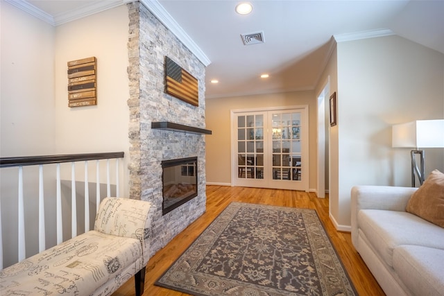 living room with visible vents, wood finished floors, ornamental molding, and a fireplace