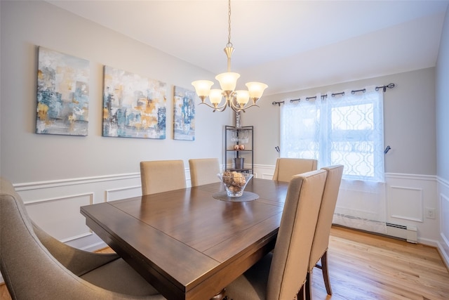 dining room with light wood-type flooring, an inviting chandelier, wainscoting, a decorative wall, and baseboard heating