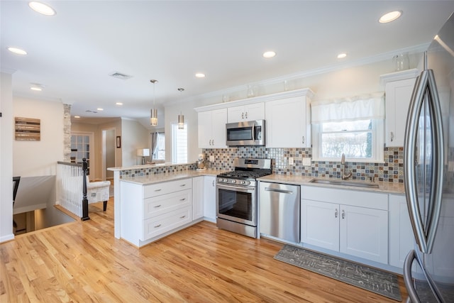 kitchen with visible vents, a sink, stainless steel appliances, a peninsula, and light countertops