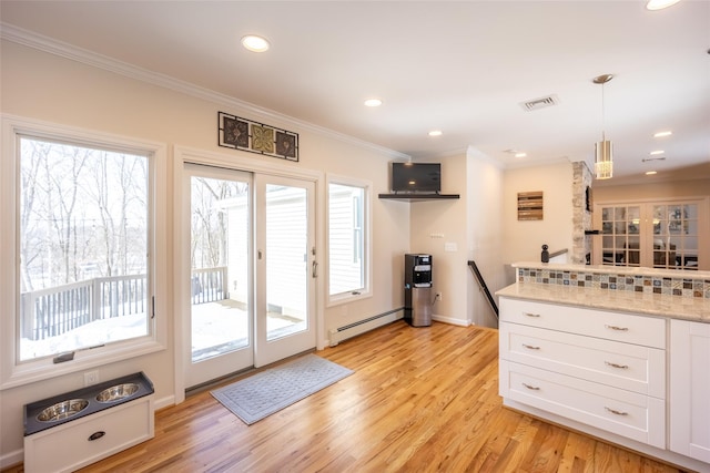 kitchen with visible vents, crown molding, baseboard heating, light wood-style flooring, and white cabinetry