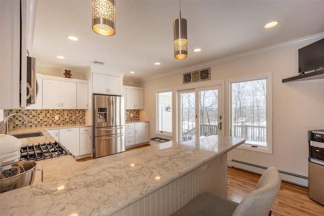 kitchen featuring light wood finished floors, a peninsula, a sink, appliances with stainless steel finishes, and crown molding