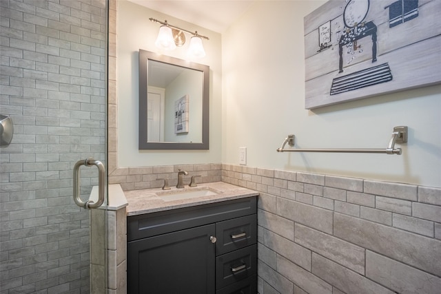 bathroom with vanity, tile walls, a stall shower, and wainscoting