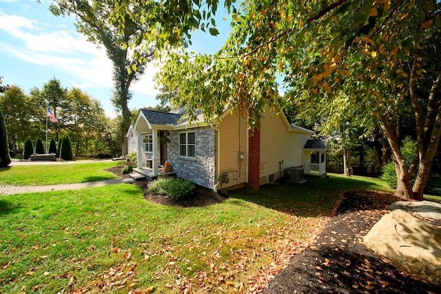 view of side of home with central air condition unit, a yard, and stone siding