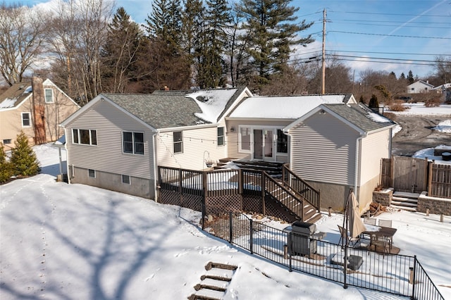 snow covered property with a patio area, a wooden deck, stairs, and fence