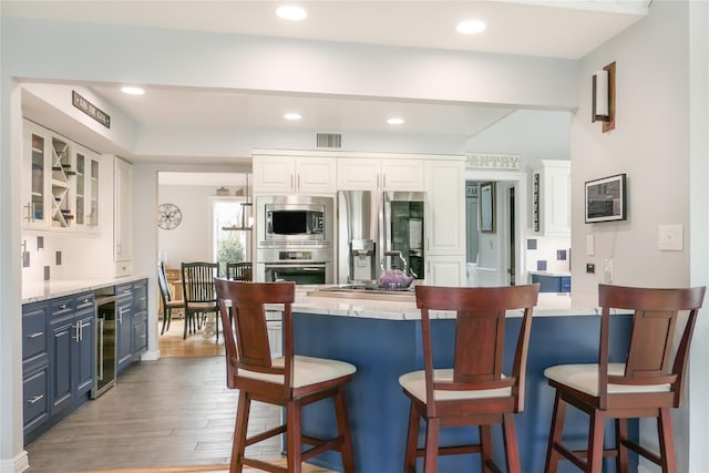 kitchen with white cabinetry, blue cabinetry, and stainless steel appliances