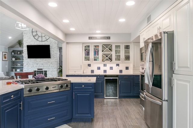 kitchen with blue cabinetry, white cabinetry, hardwood / wood-style floors, stainless steel appliances, and wine cooler