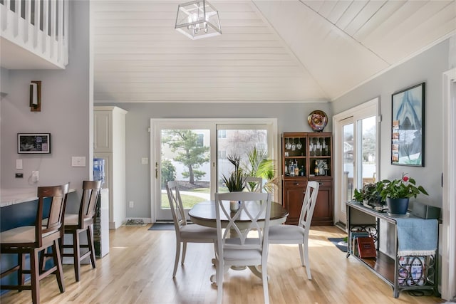 dining area with vaulted ceiling, ornamental molding, a notable chandelier, and light wood-type flooring