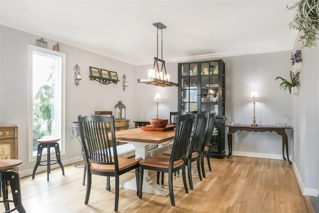 dining space with crown molding, a chandelier, and light wood-type flooring