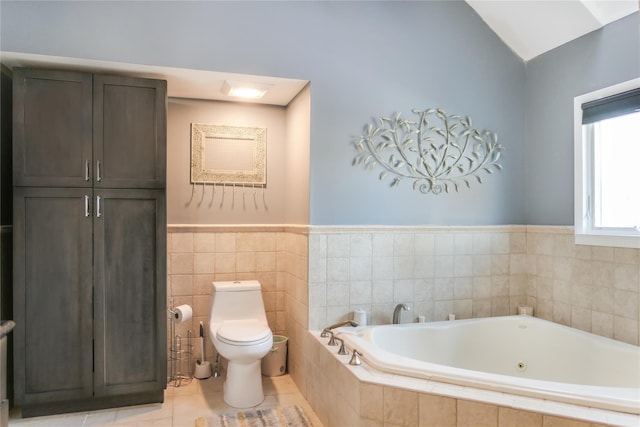 bathroom with tile patterned flooring, tiled bath, tile walls, and toilet