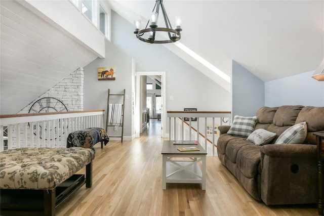 living room with high vaulted ceiling, plenty of natural light, a chandelier, and light hardwood / wood-style floors