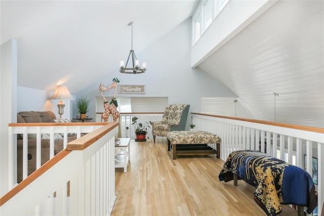 living area with high vaulted ceiling, an inviting chandelier, and light hardwood / wood-style floors