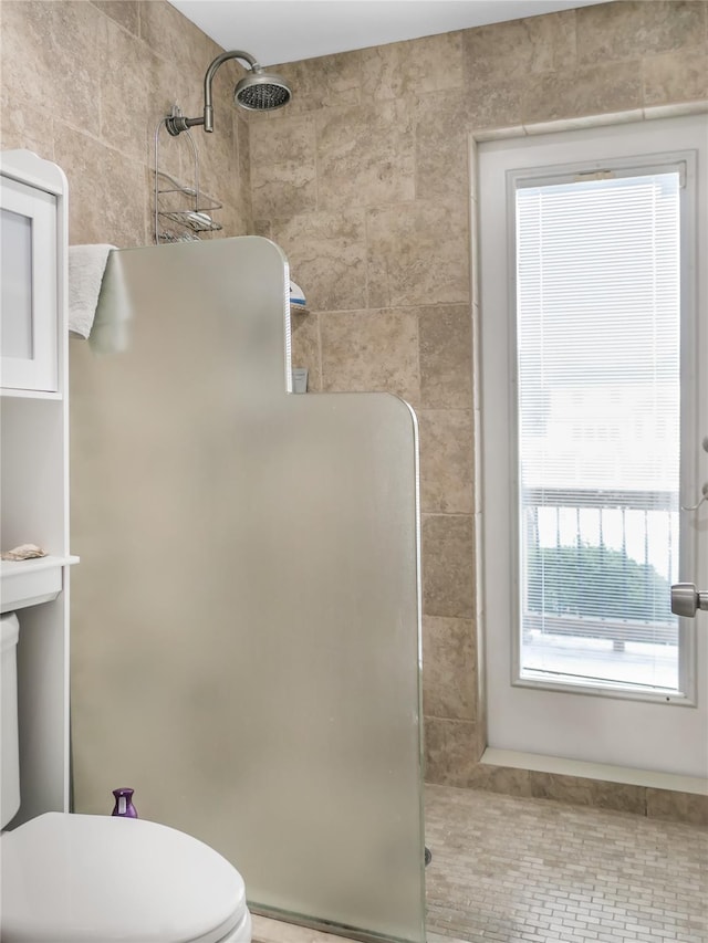 bathroom featuring a tile shower, tile walls, and toilet