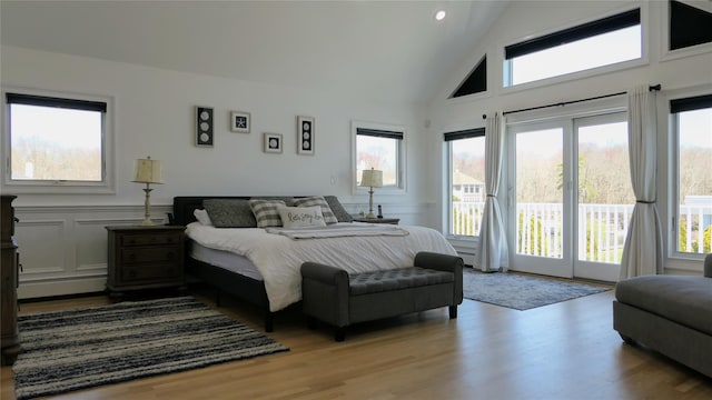bedroom with a decorative wall, light wood-style flooring, and access to exterior