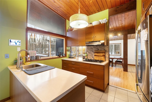 kitchen featuring sink, light tile patterned floors, kitchen peninsula, pendant lighting, and stainless steel appliances