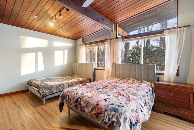 bedroom featuring multiple windows, vaulted ceiling with beams, and light wood-type flooring